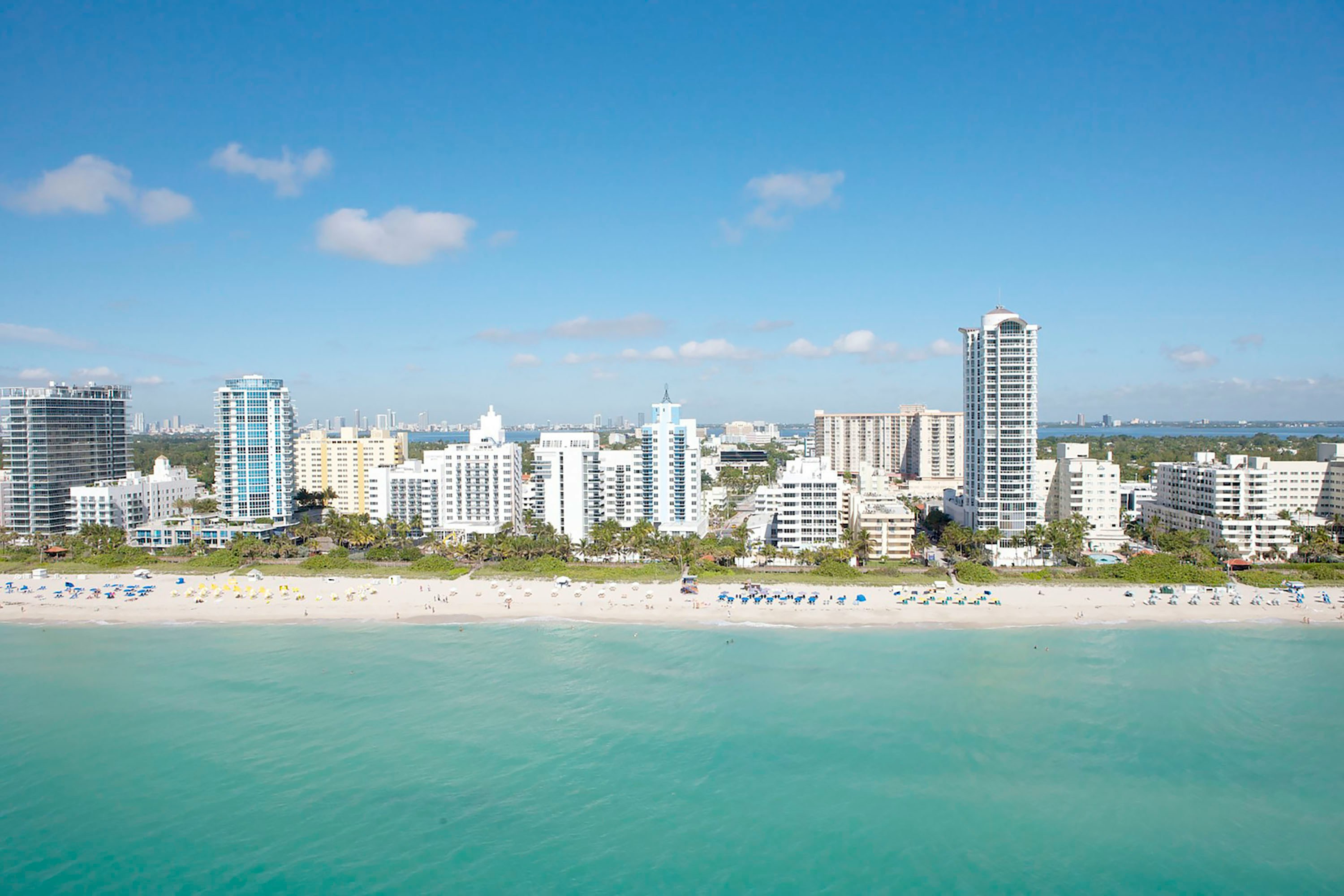 Aerial view of the Miami Beach coastline with turquoise ocean, sandy beach, and beachfront hotels
